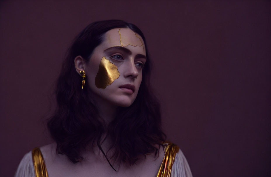 Contemplative woman with golden eye patch and tears on muted background