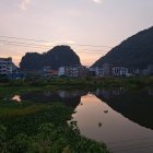 Traditional Chinese Pagoda and Pavilions by Calm Lake with Boat and Mountains at Dusk