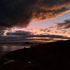 Fiery orange glow in dramatic night sky near coastline