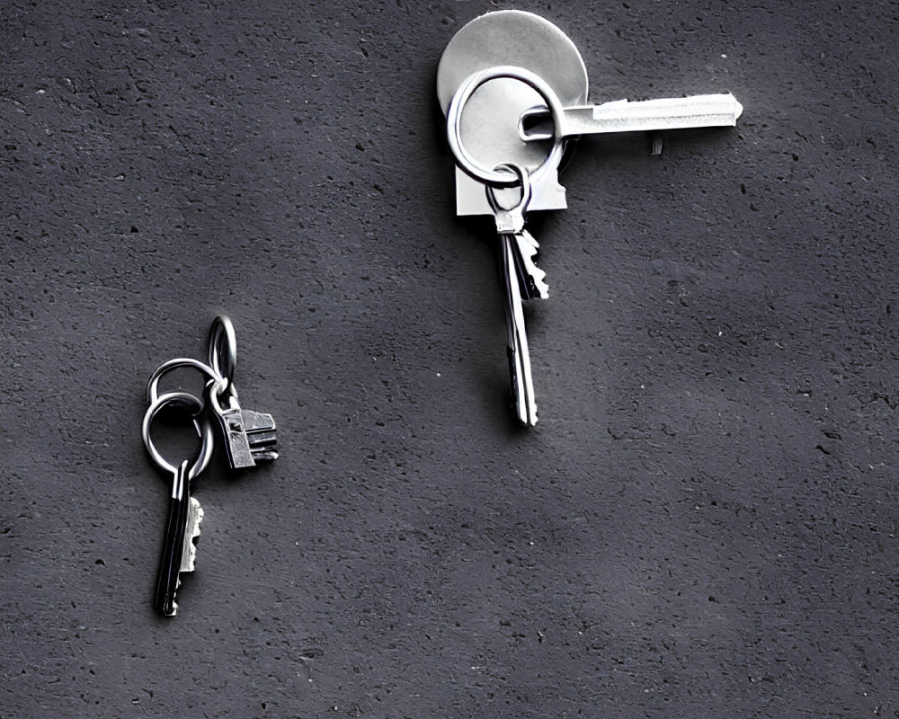 Keys inserted into textured gray wall with another set hanging