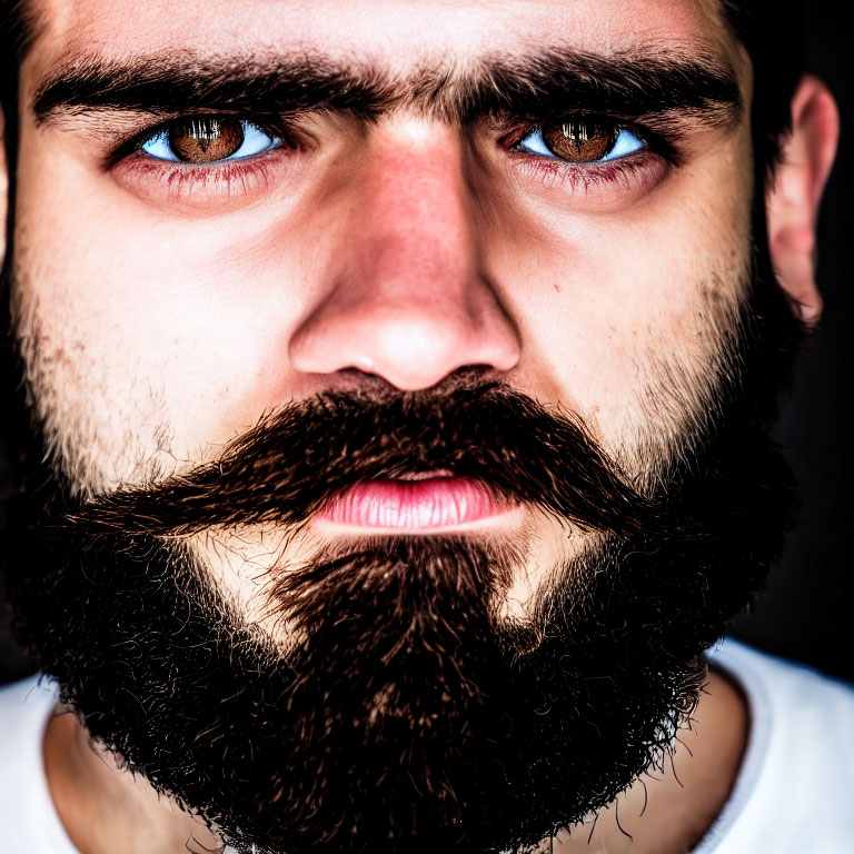 Intense blue-eyed man with dark beard on dark background