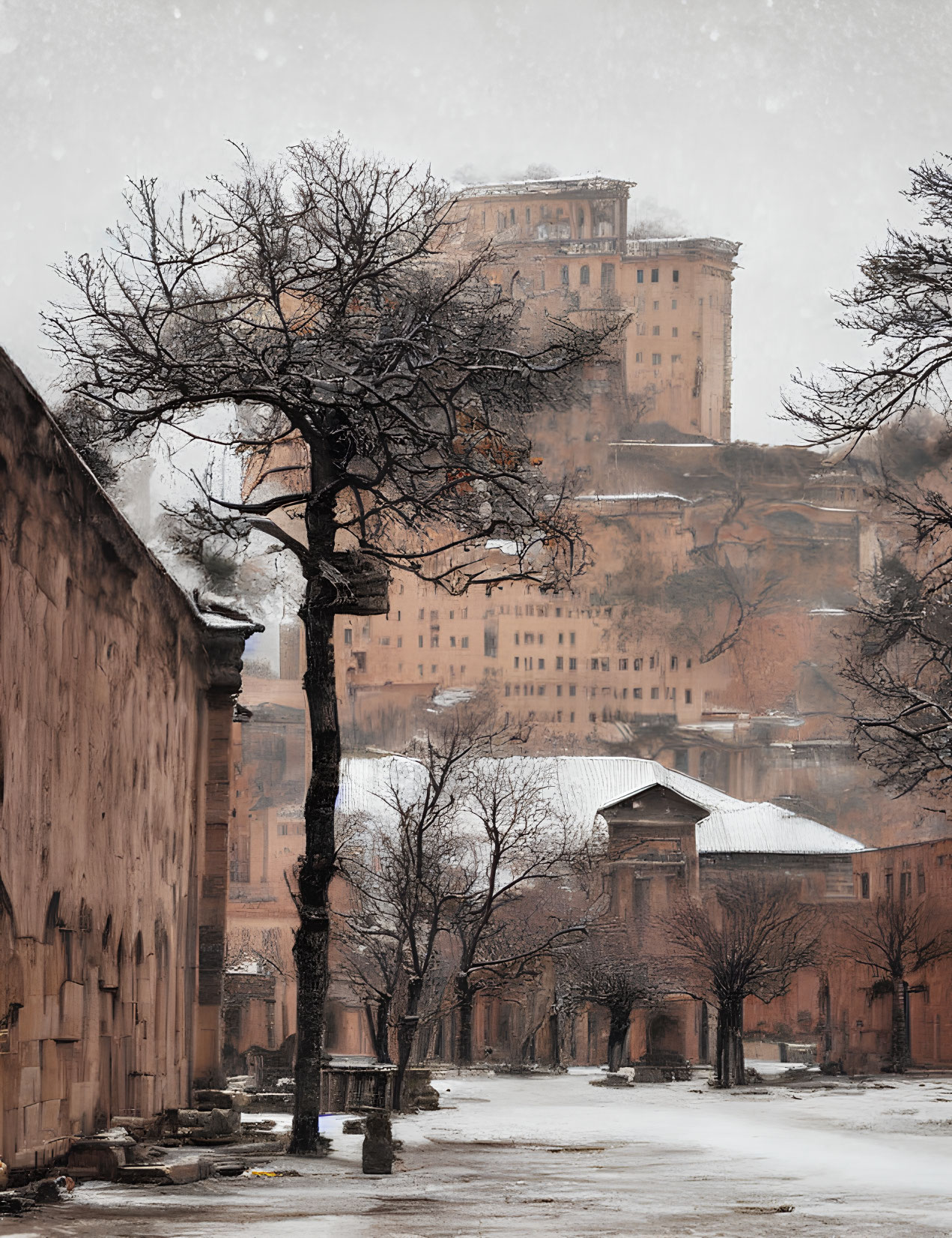 Snowy landscape with leafless tree and historic structure on hilltop