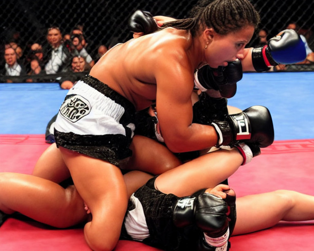 Female MMA fighters in grappling position on red mat, one in dominant black and white shorts.