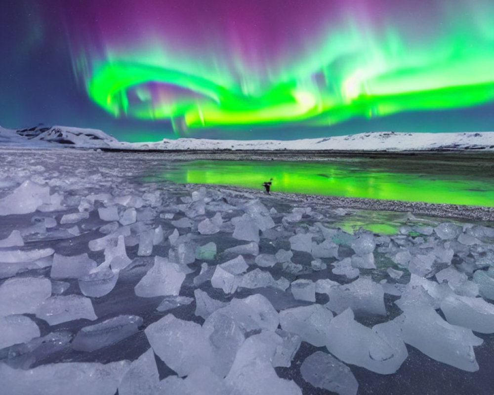 Person under vibrant aurora borealis in frozen landscape at night