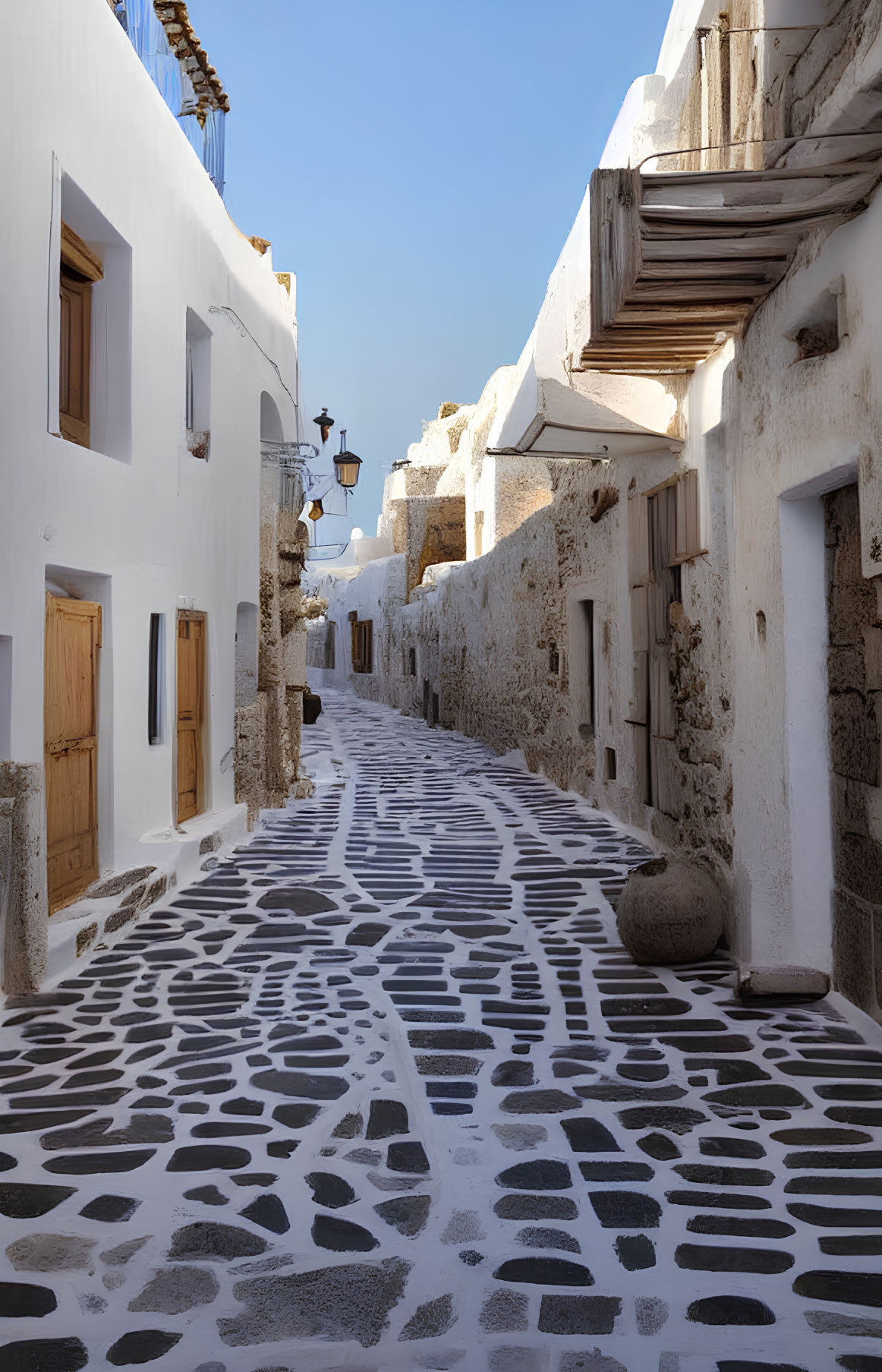 Traditional white-washed village alley with pebbled pattern under clear blue sky