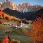 Scenic painting of tranquil village with autumn trees and snow-capped mountains