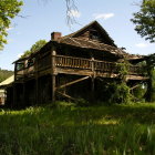 Dilapidated Victorian mansion in overgrown grass with dark sky