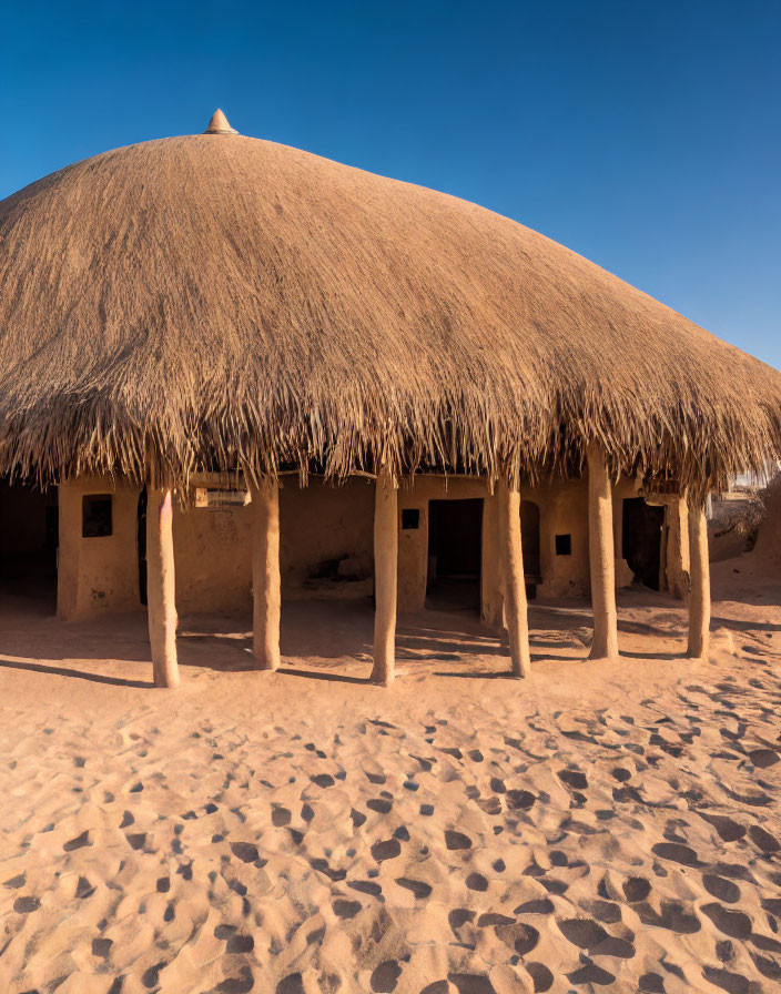 Traditional Thatched-Roof Mud Hut on Sandy Ground