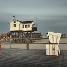 Tranquil coastal landscape with stone fortress, white house, boats, and moody sky