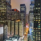 Vibrant night cityscape with illuminated skyscrapers and rain-soaked streets