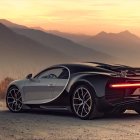 Blue sports car on rocky overlook with golden-lit mountains