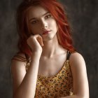 Red-haired woman with ornate tattoos and jewelry on dark backdrop