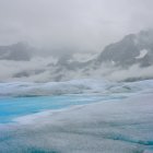 Arctic landscape with low sun, icebergs, and lone figure