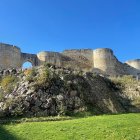 Medieval stone fortress with ancient walls and arched windows under clear blue sky