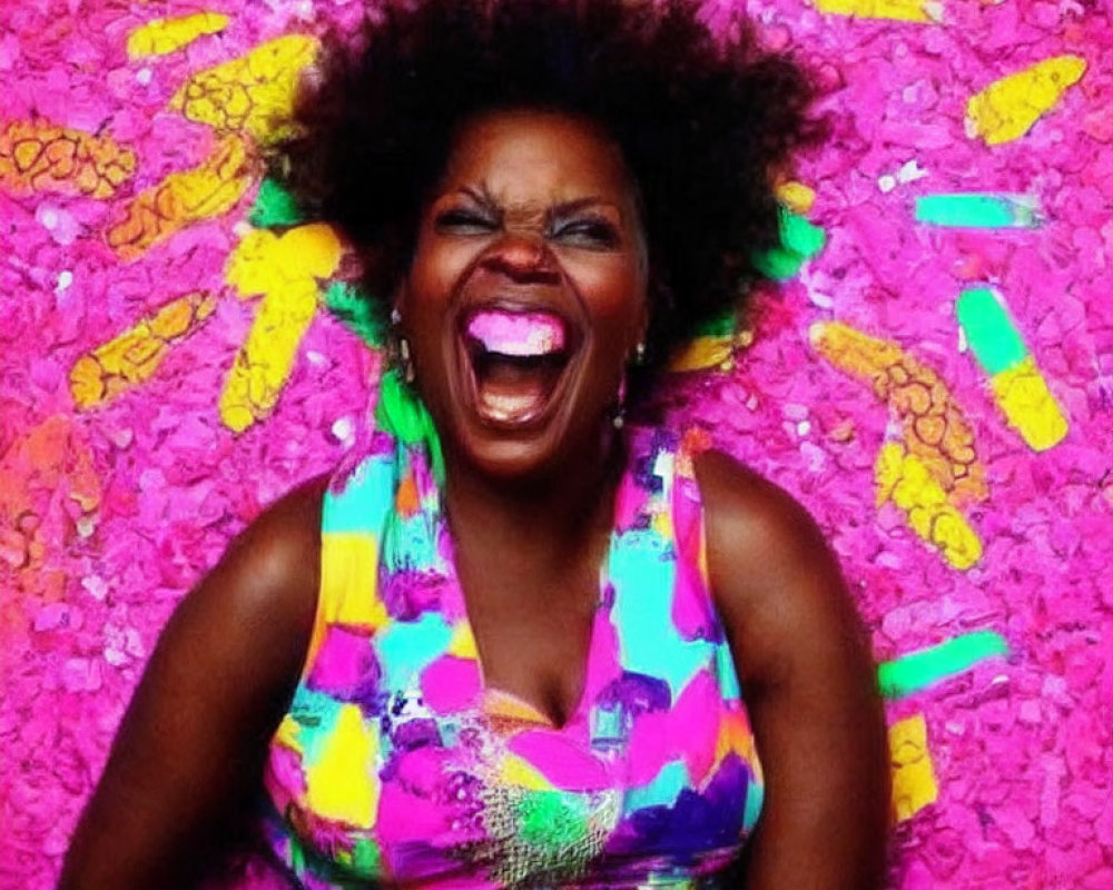 Smiling woman with curly hair in colorful top on vibrant pink background