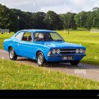 Blue Vintage Car with Oversized Wheels Flying Over Grass Field with Woman Posing