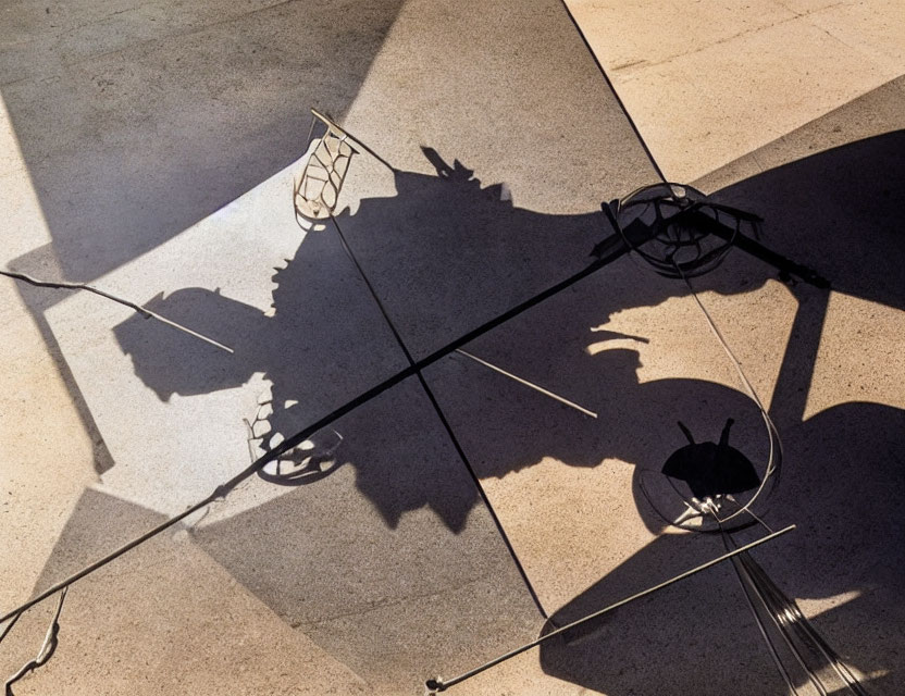 Abstract outdoor scene: table, chairs, long shadows, light & dark pattern