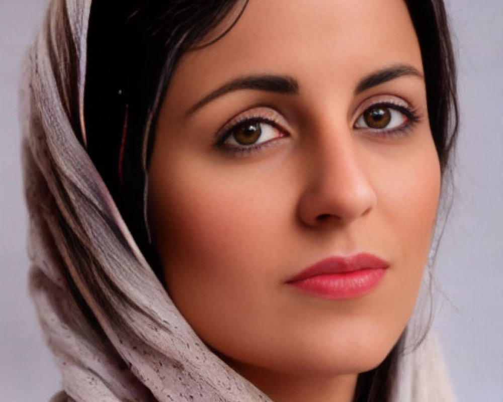 Dark-haired woman in red top and head scarf gazes calmly forward.