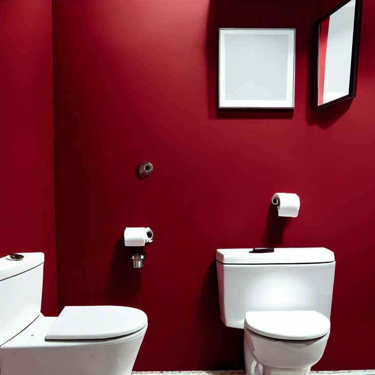 Vivid red wall in modern bathroom with two side-by-side white toilets and empty frames