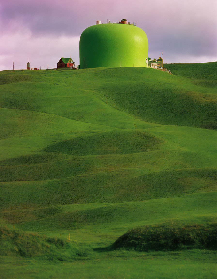 Green spherical structure on rolling hills with small red-roofed house