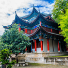 Traditional Japanese pagoda in lush greenery and stone staircases under clear blue sky