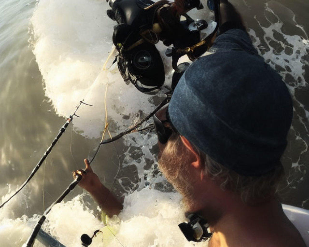 Person fishing with cap in sea as wave approaches, another person in scuba gear underwater