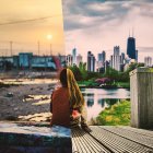 Woman admires cityscape blending with nature on wooden deck