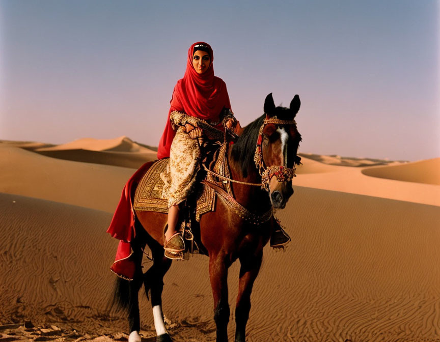 Woman in red headscarf on decorated horse in desert landscape