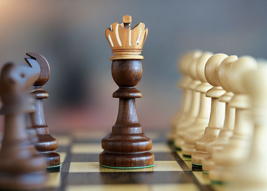 Wooden chess queen close-up on board with blurred pieces in background