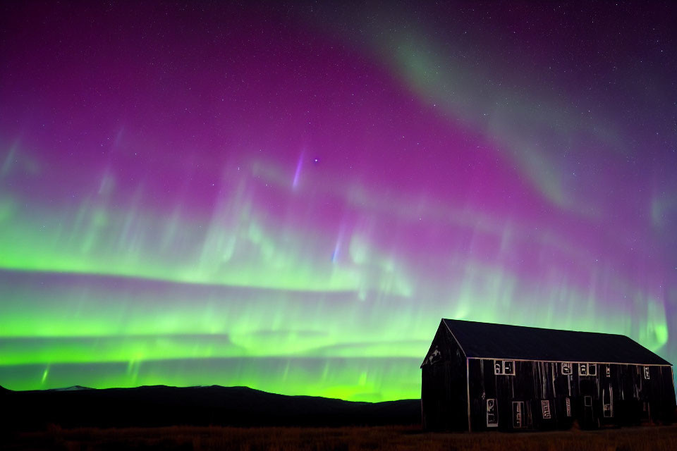 Majestic purple and green aurora borealis over dark building