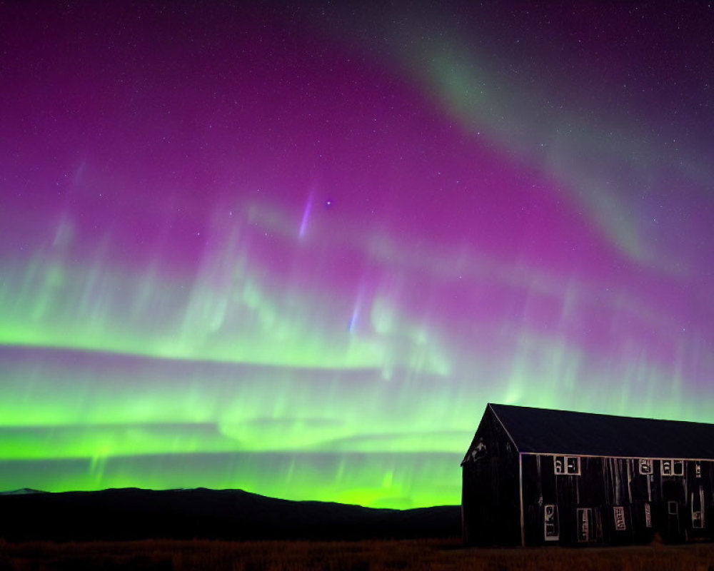 Majestic purple and green aurora borealis over dark building