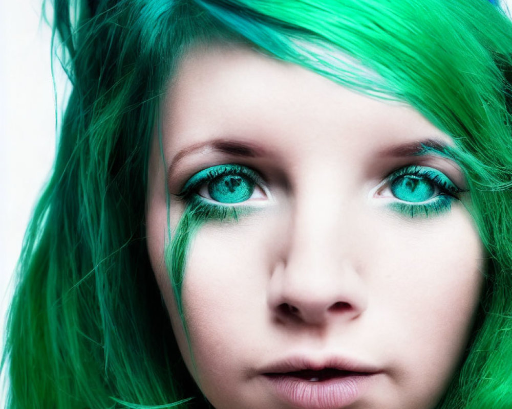 Close-up of person with vibrant green hair and matching eye makeup, showcasing blue eyes and pale skin