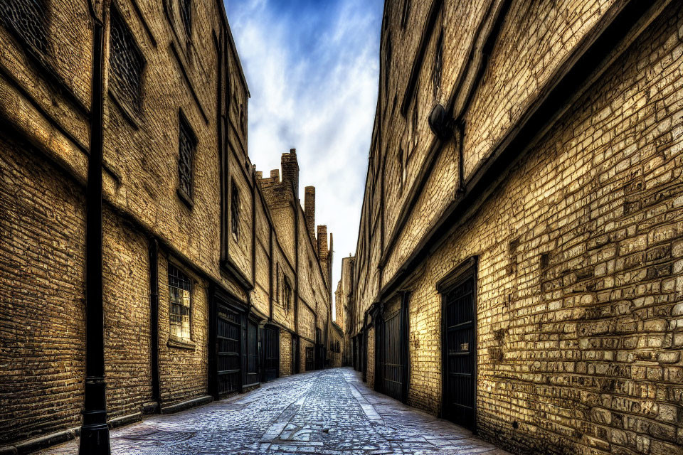 Historic cobblestone alley between old brick buildings under deep blue sky