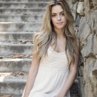 Surreal portrait of woman with flowing hair in white dress against dreamy backdrop