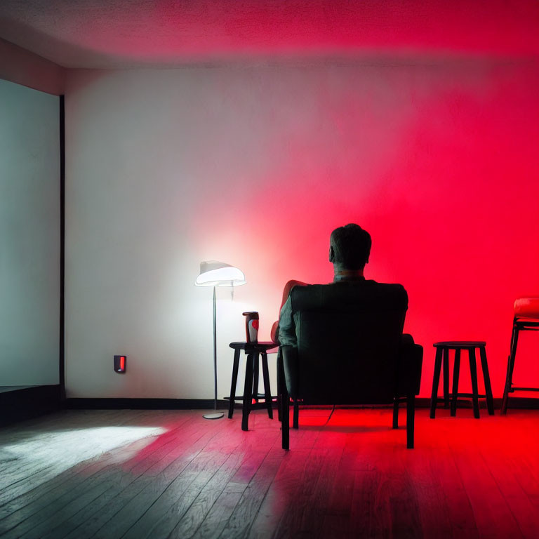 Person in Dark Room with Red Light, Chair, Lamp, and Cup