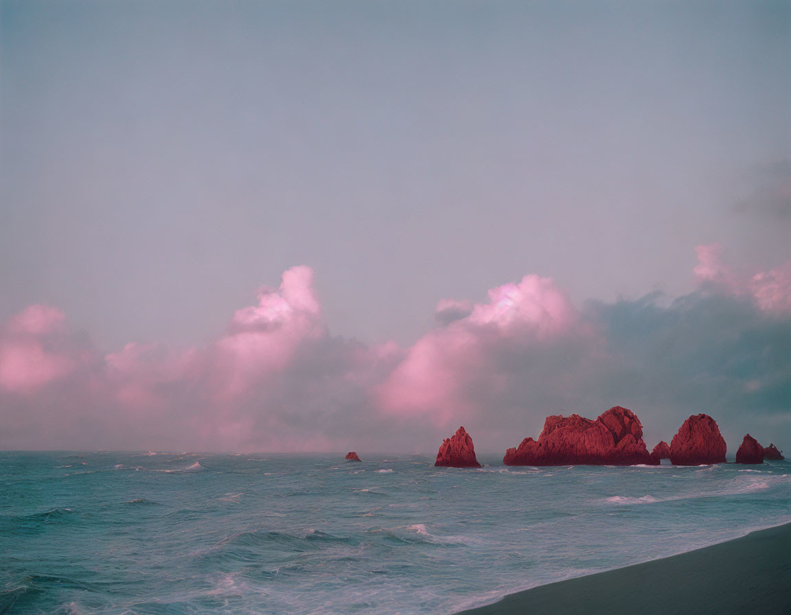 Tranquil beachscape at twilight with pastel-hued clouds and rocky outcrops