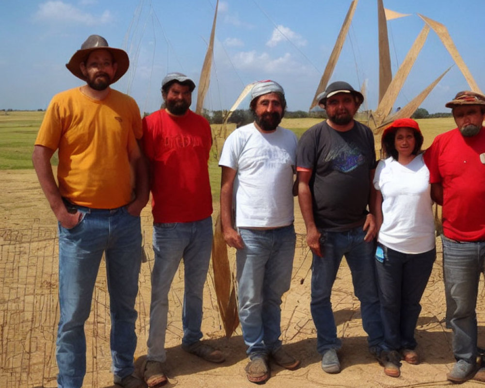 Six people posing outdoors with a large wooden structure under a clear sky