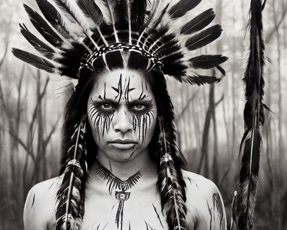 Monochrome portrait of person in feathered headdress with face paint, gazing intensely in forest.