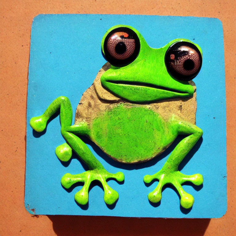 Green Frog Magnet with Oversized Googly Eyes and Outstretched Limbs on Blue Background