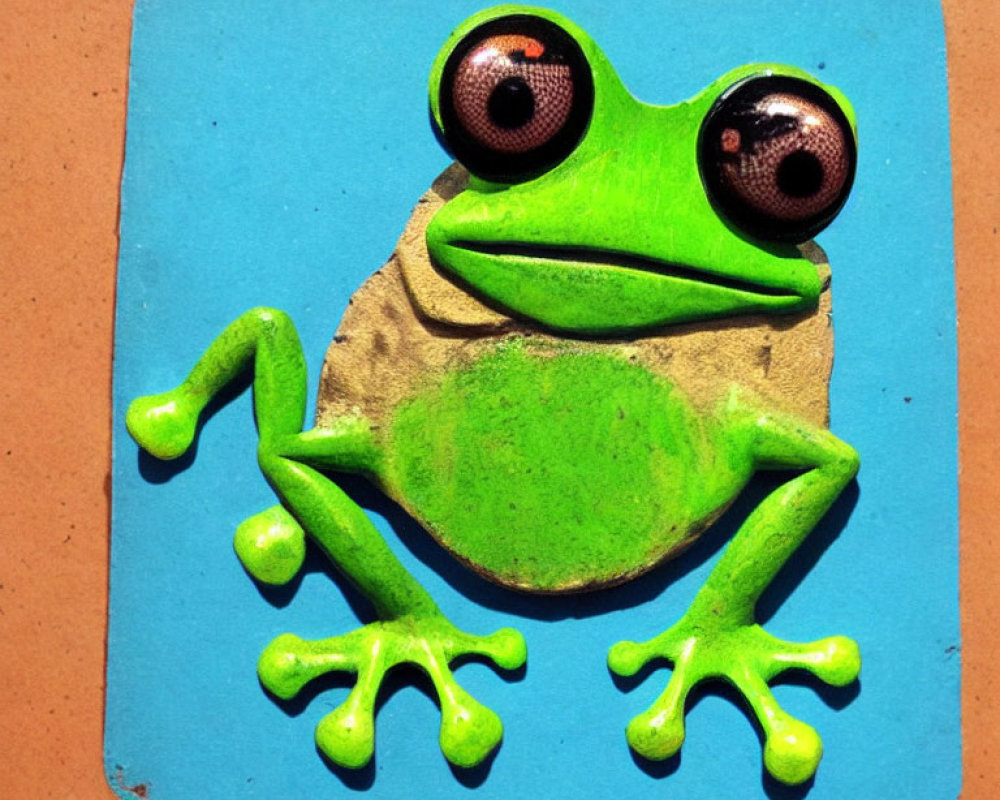 Green Frog Magnet with Oversized Googly Eyes and Outstretched Limbs on Blue Background