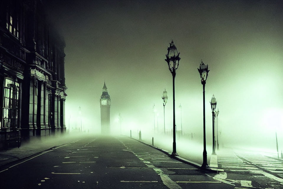 Misty street lamps on deserted road to fog-covered clock tower