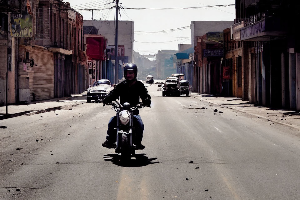 Urban street scene: Motorcyclist riding past buildings and cars on sunny day