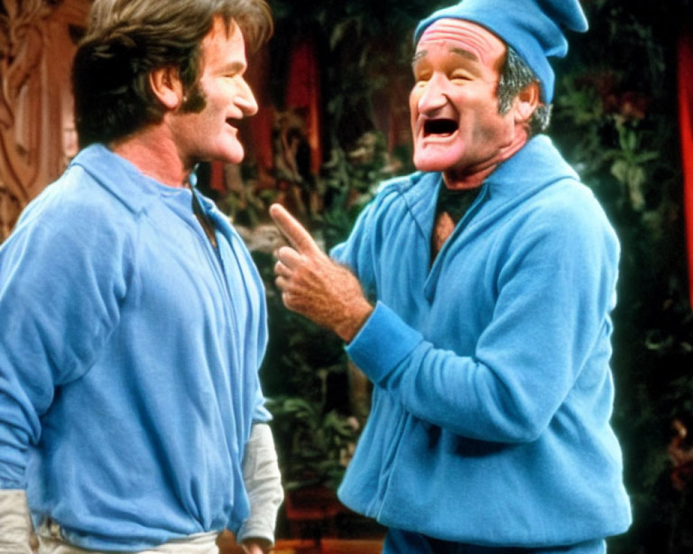 Two men in blue shirts laughing, one wearing a woolen hat