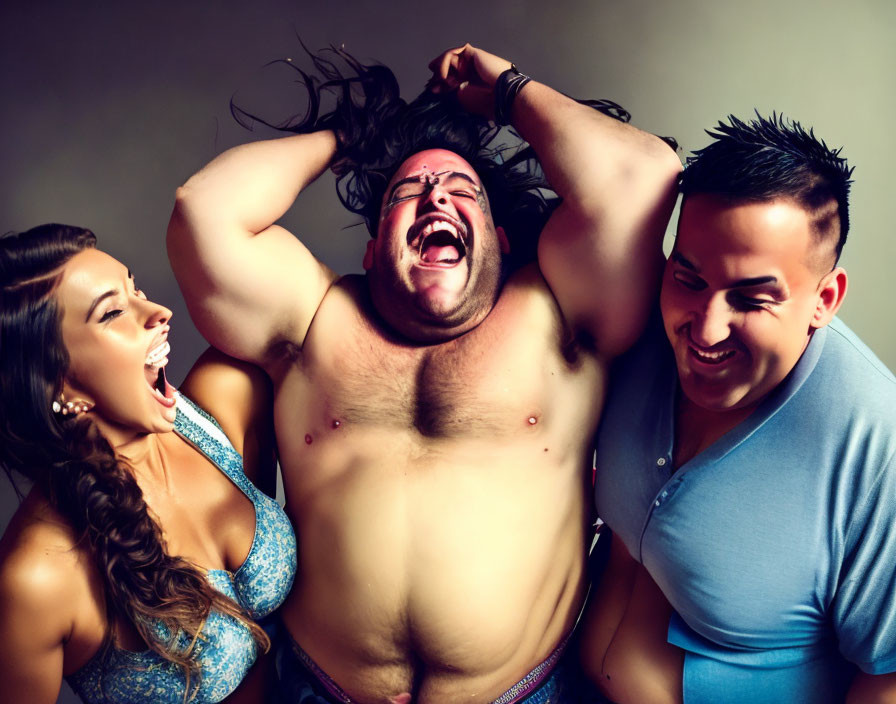 Three people posing joyfully with wrestling mask, hair pulling, smiling on gray backdrop