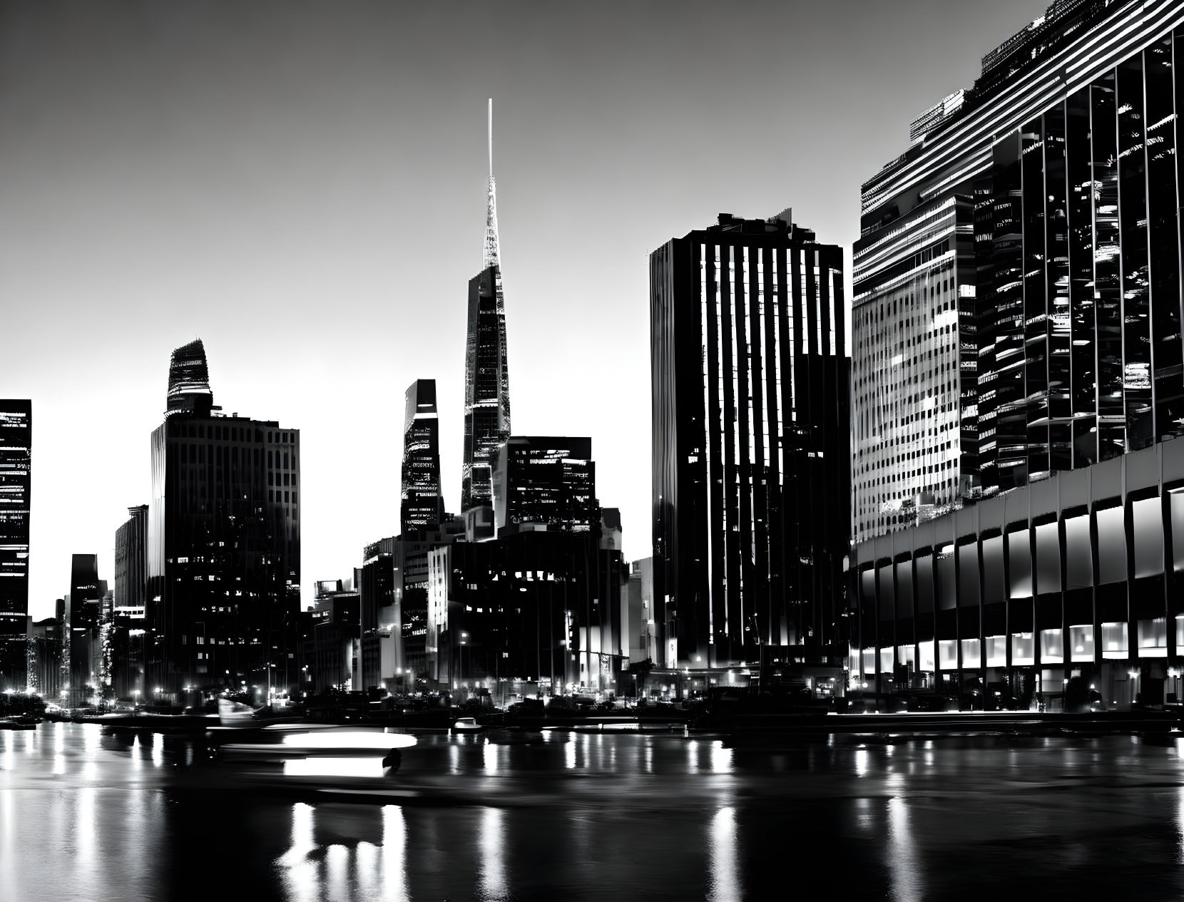 Monochrome night cityscape with illuminated skyscrapers reflected in calm river