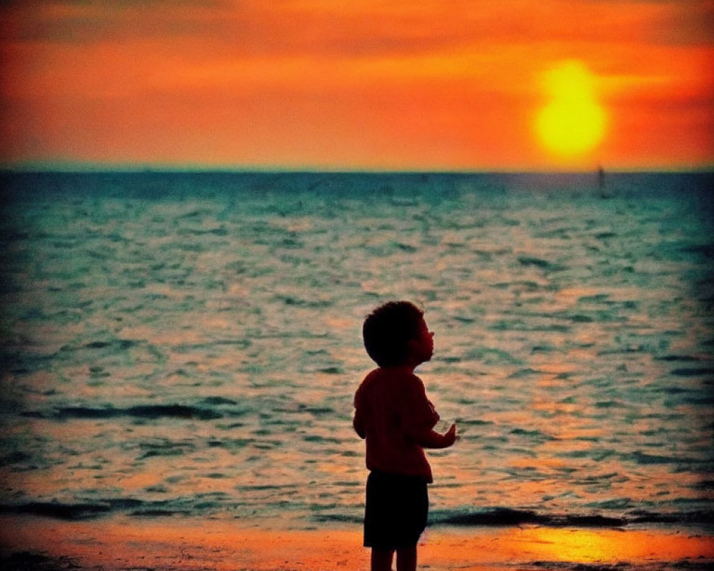 Child Silhouetted Against Vibrant Sunset at Beach