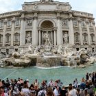 Historic Fountain Surrounded by Tourists and Ornate Buildings in Blue Sky