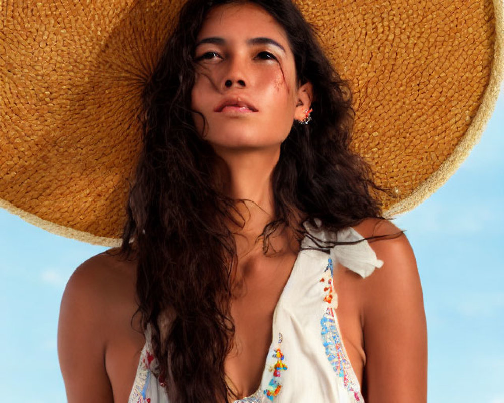 Young woman in straw hat and sundress on beach under clear blue sky