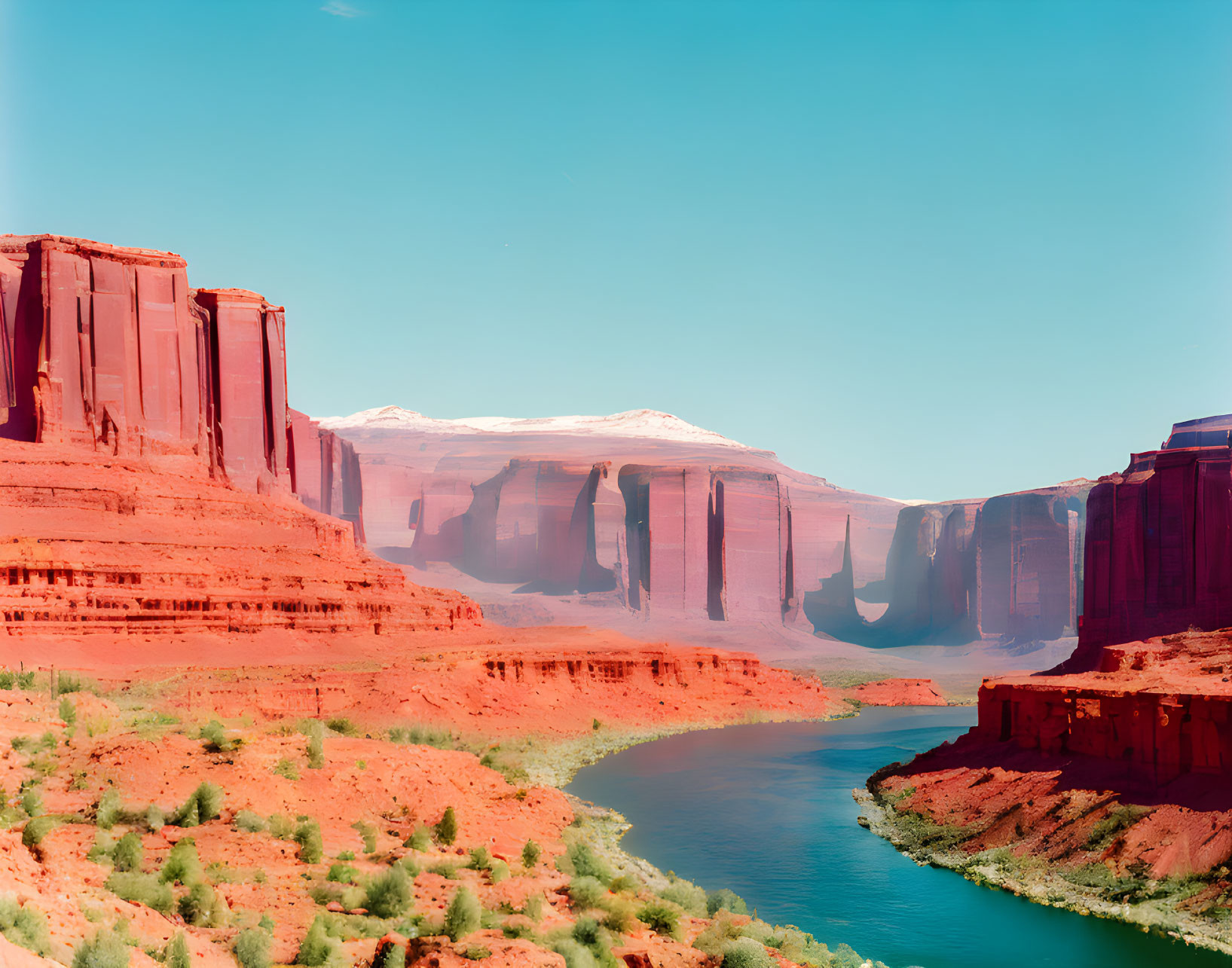 Tranquil river in red rock canyon under blue sky with snowy peaks