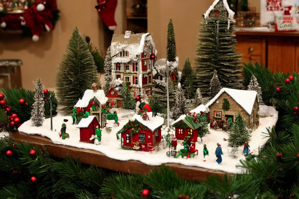 Snow-covered miniature festive village with pine trees and Christmas decorations